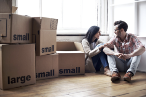 Young couple sitting on the floor of an appartment with moving boxes